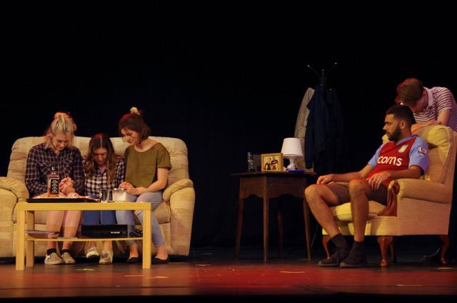 A living-room scene with friends on a sofa and an armchair