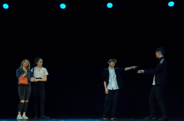 Pupils and a teacher pointing across the stage
