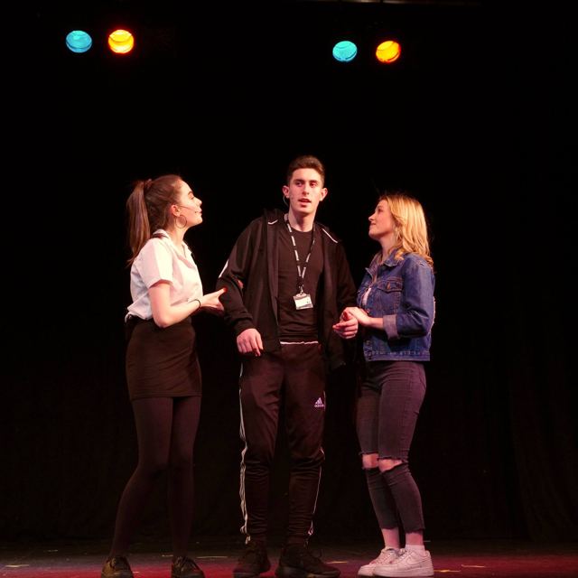 A young man in a tracksuit top between two girls