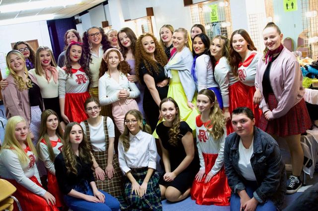 Cast members in costume posing together backstage
