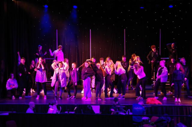 The company performing a number under purple and blue light
