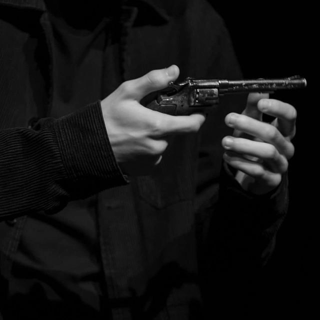 Black-and-white close-up of hands holding a gun