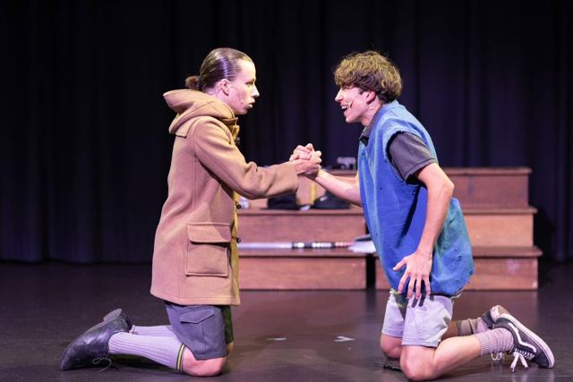 Two boys kneeling face to face, shaking hands