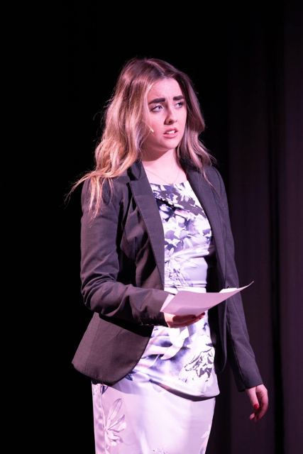A young woman in a blazer reading a letter