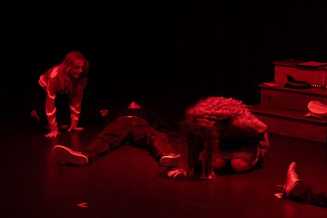Performers collapsed on the floor under red light
