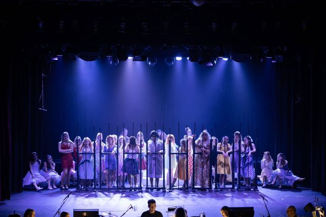 A wide view of the stage with the cast behind bars