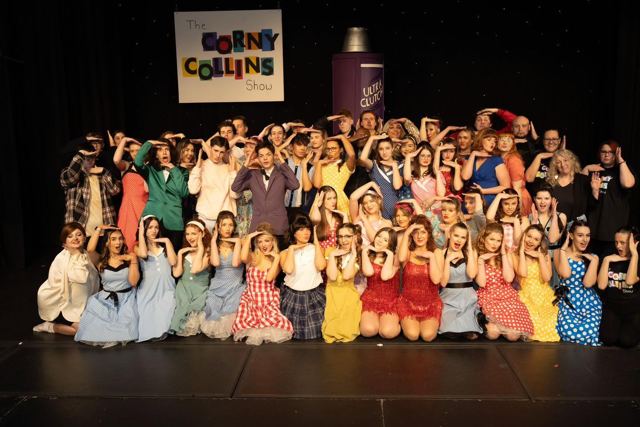 The full company celebrating on stage