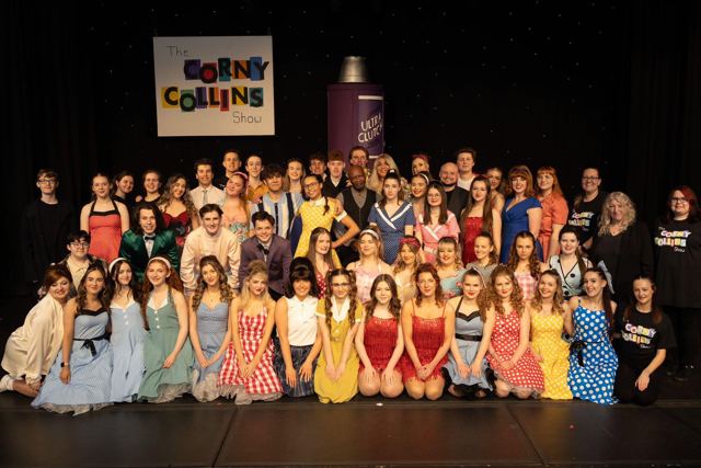 The full company posed on stage under the Corny Collins Show sign