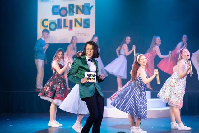 Dancers performing in front of the Corny Collins Show sign