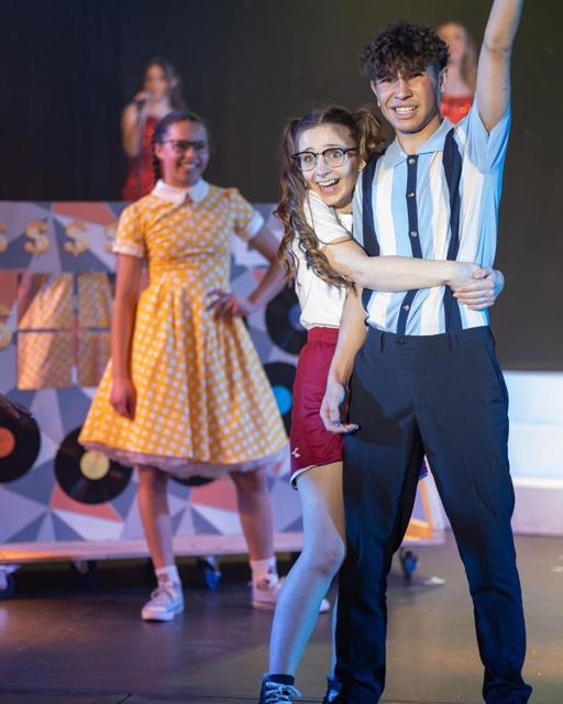 A couple dancing beside a performer in an orange dress