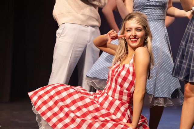 A performer in a red gingham dress smiling