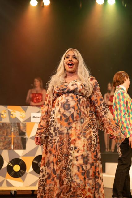 A performer in a leopard-print kaftan and blonde wig singing