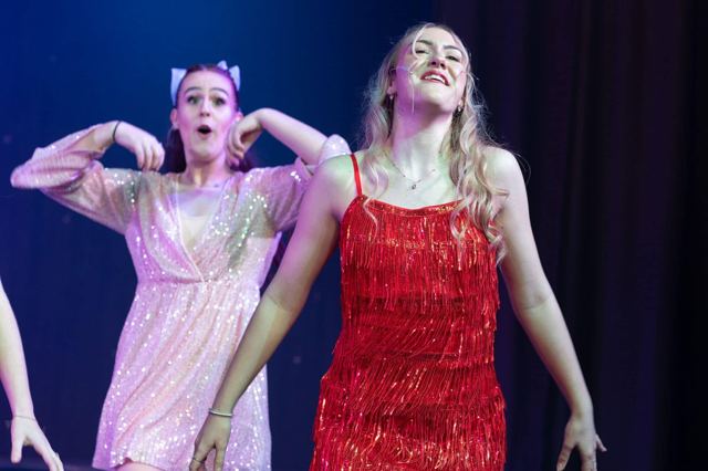 Two performers in pink and red dresses dancing