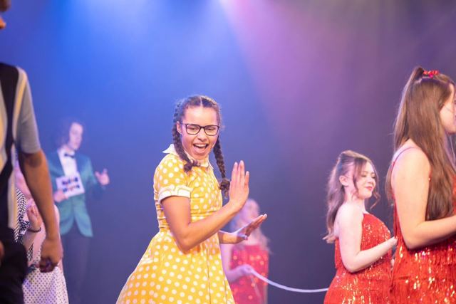 A performer in a yellow polka-dot dress dancing