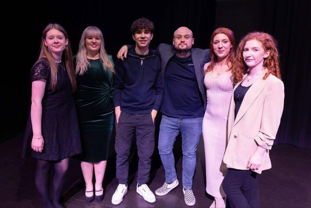 The cast standing together on stage