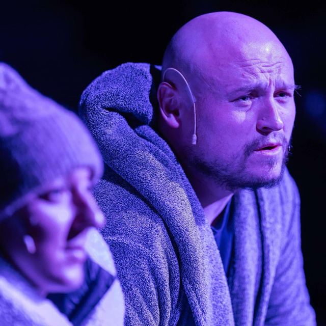 A man in a blue dressing gown under cool blue light