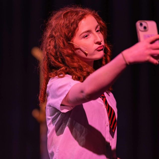 A young woman in a school shirt and tie taking a selfie