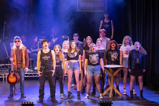 The company lined up across the stage under blue light