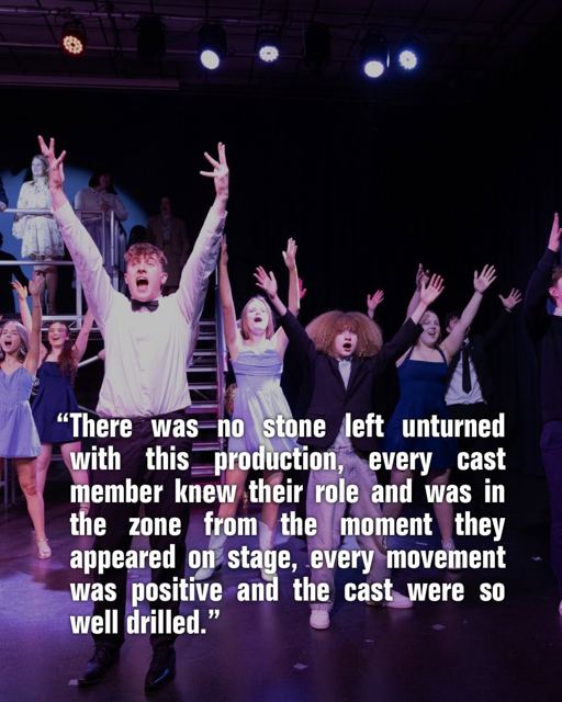 The company with arms raised, with a review quote