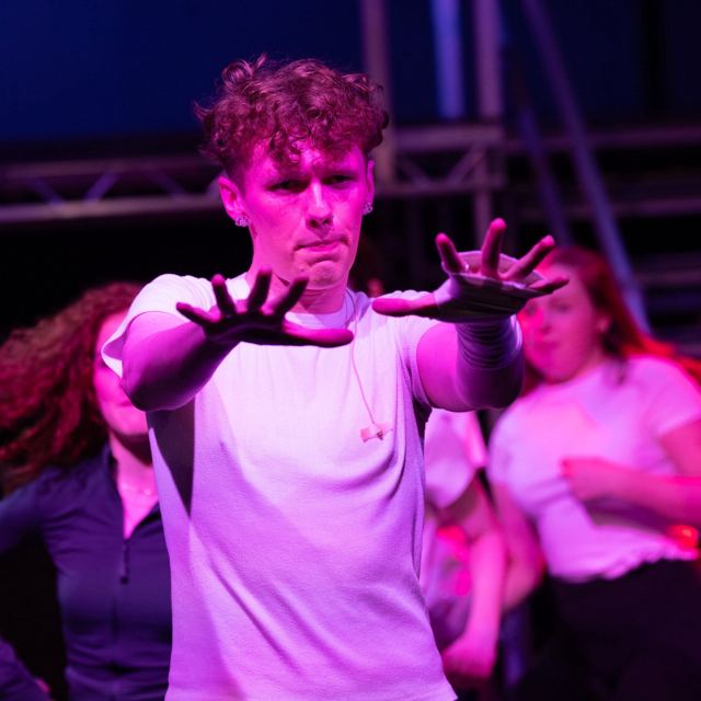 A young man reaching out under pink light